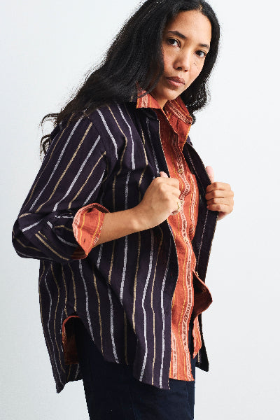 Woman wearing a striped shirt over a button-up shirt on a white background