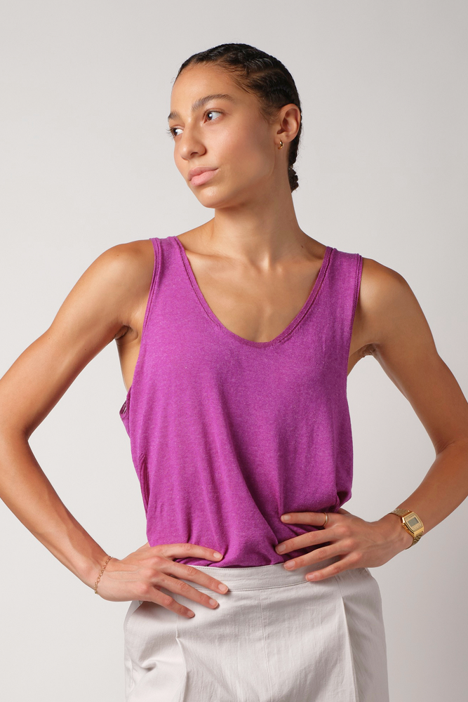 Person wearing a purple silk & linen tank top and light grey linen pants against a plain background
