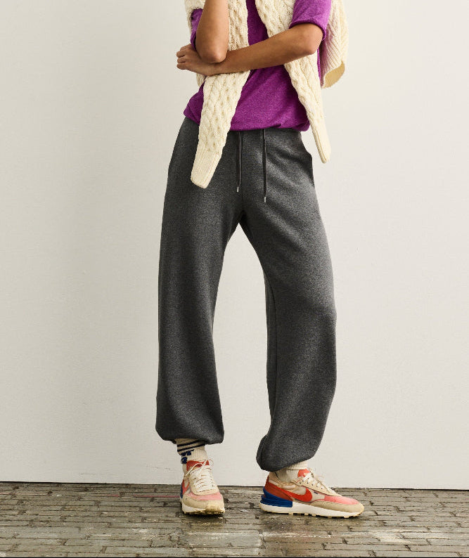 women with baseball cap wearing an aran sweater over a silk seamless merino sweater over merino sweatpants with sneakers