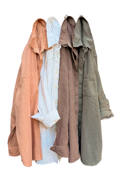 four linen organic cotton buttodown shirts hanging in a row, tangerine, white, brown, sage
